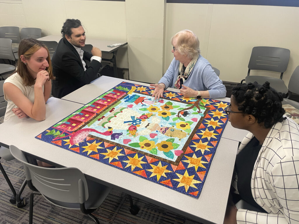 Project team members examine a Baltimore Album Quilt along with quilting expert Mimi Dietrich.